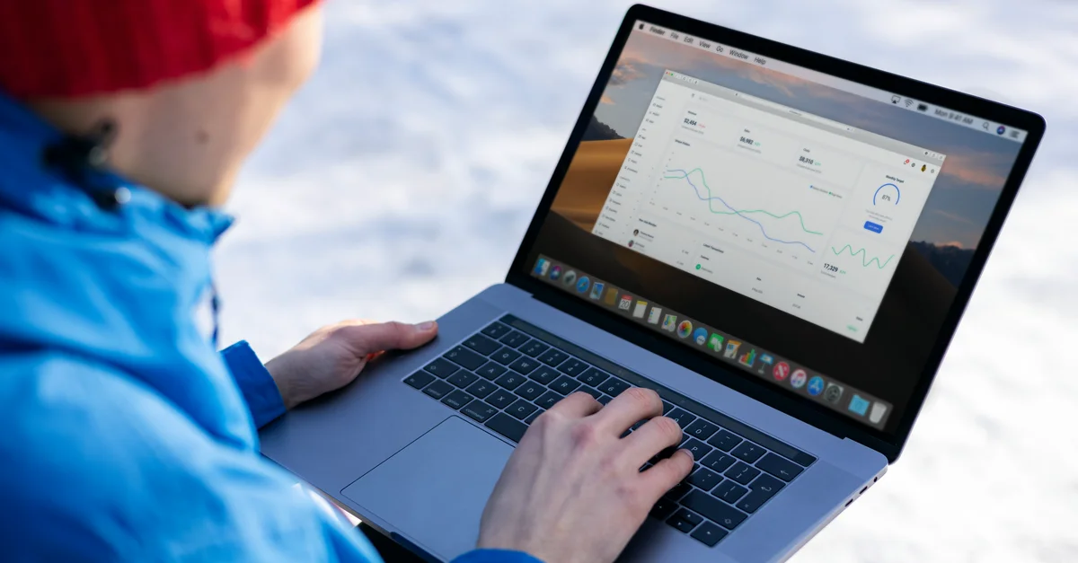 Personne travaillant sur un ordinateur portable en analysant des graphiques dans un cadre extérieur en hiver.