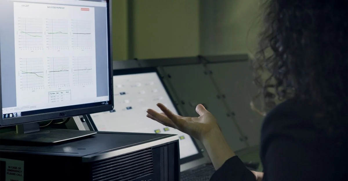 Une femme analyse des données sur un écran d'ordinateur dans un bureau moderne, se concentrant sur la recherche technologique.